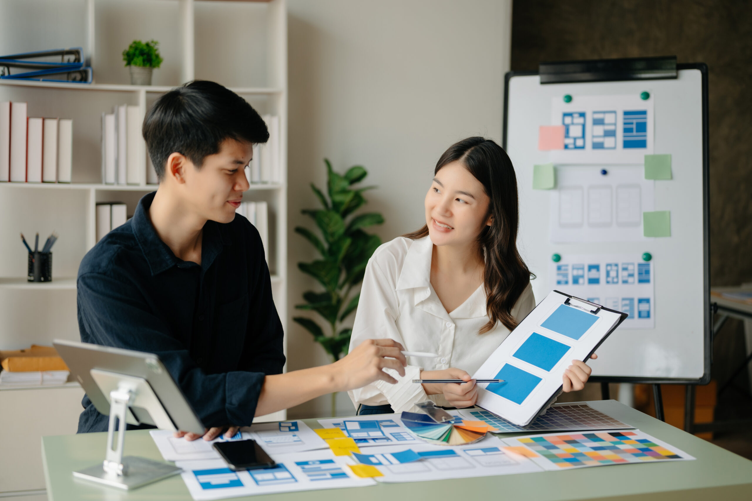 Asian businessman and woman people meeting in green office. Employee brainstorm and work as team, plan and discuss project by point on paper and tablet.